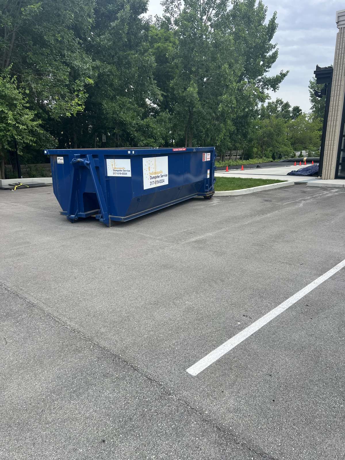 A navy Indianapolis Dumpster Service roll off container in Carmel. On the driveway, set back from the basketball hoop.