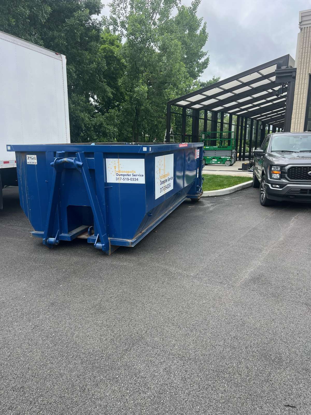 A navy Indianapolis Dumpster Service roll off container in Carmel. On a wide driveway with the front walk left clear.
