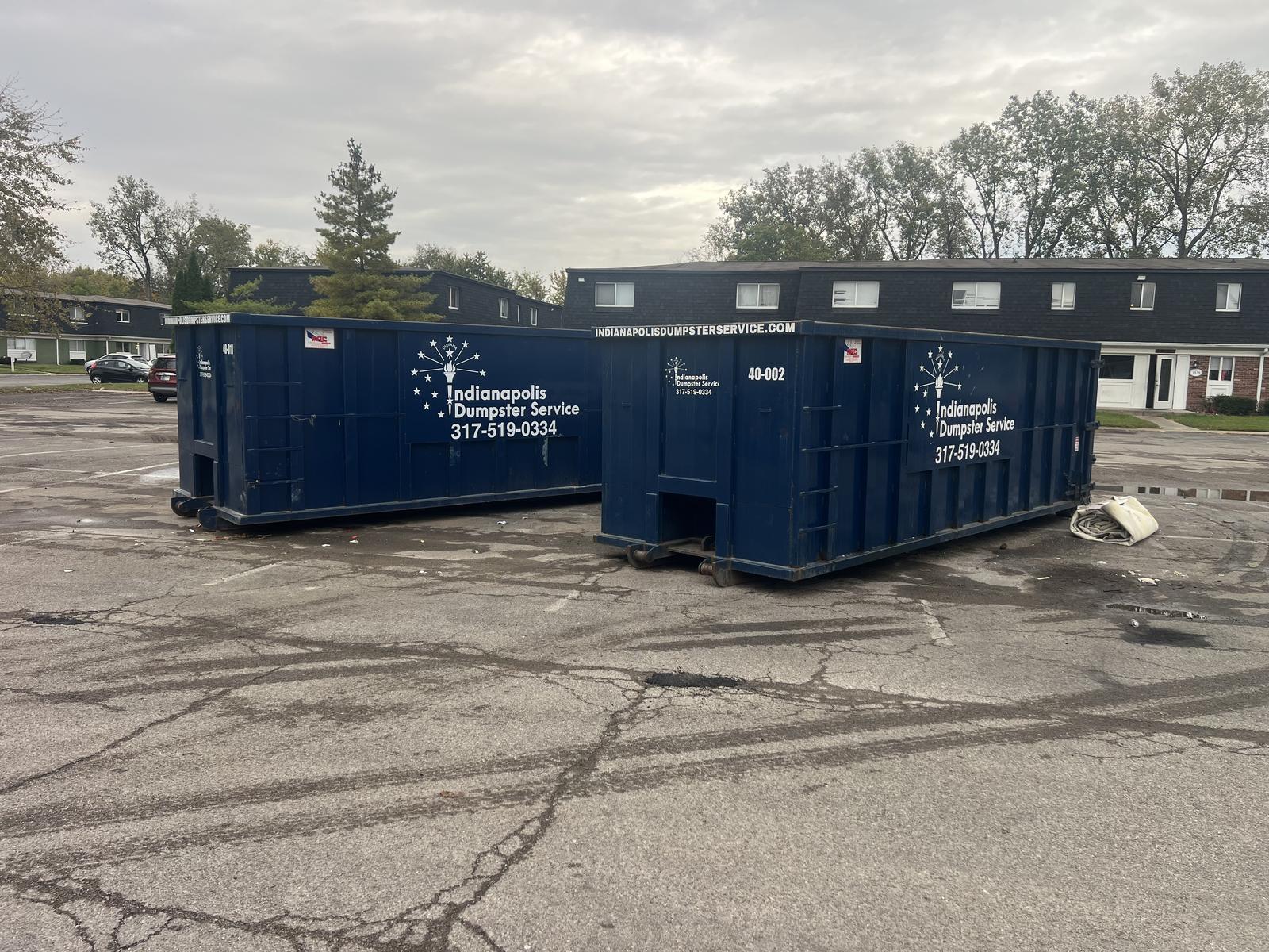 A navy Indianapolis Dumpster Service roll off container in Indianapolis. Two dumpsters side by side in an apartment complex lot.