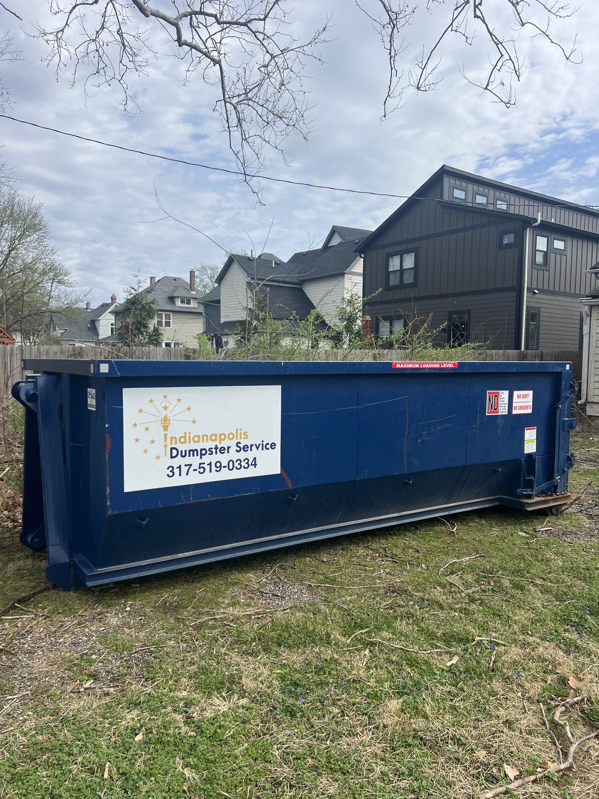 A navy Indianapolis Dumpster Service roll off container in Indianapolis. Beside a new build before the driveway was poured.