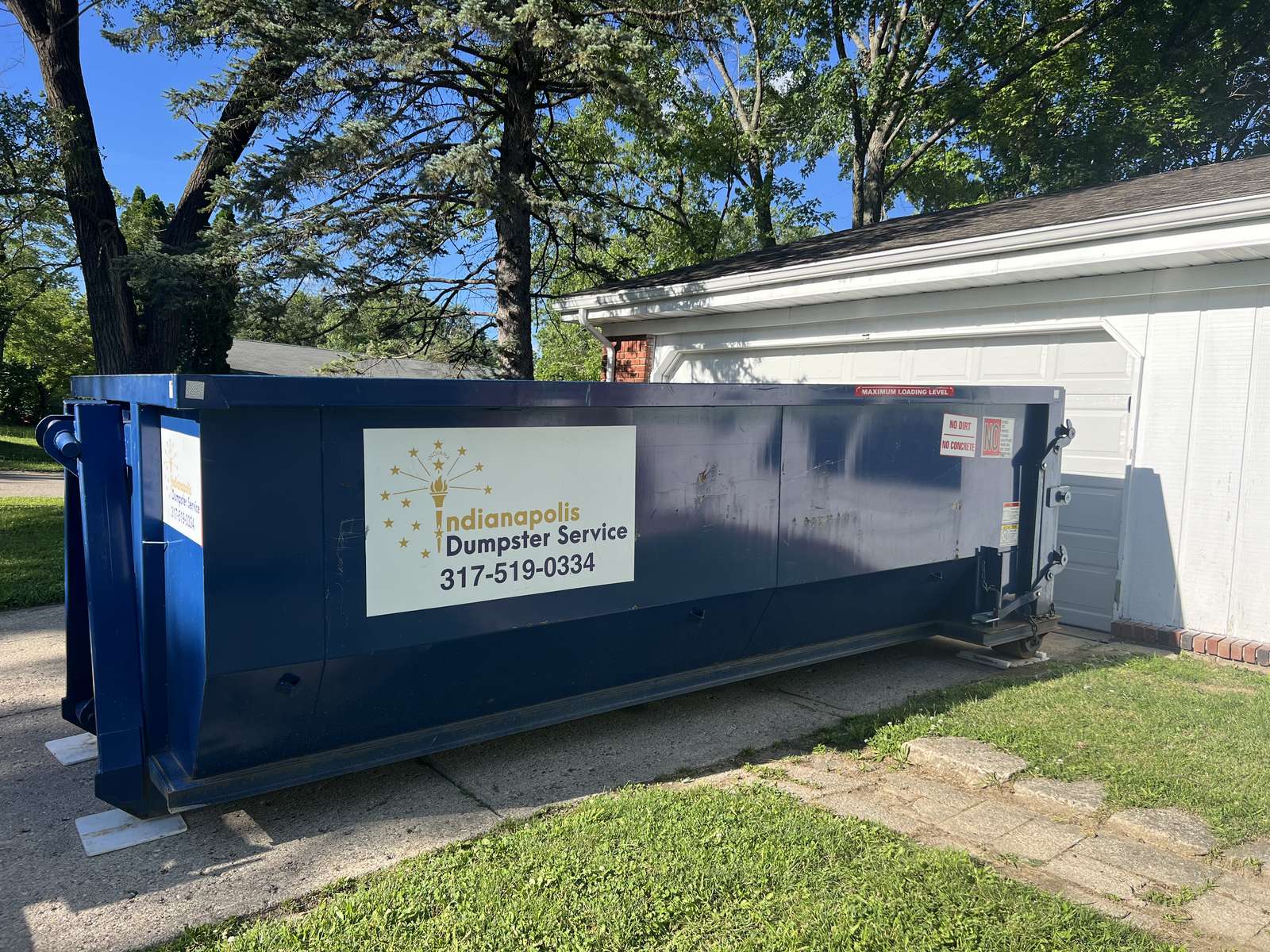A navy Indianapolis Dumpster Service roll off container in Indianapolis. A roofing job with the dumpster at the foot of the driveway.