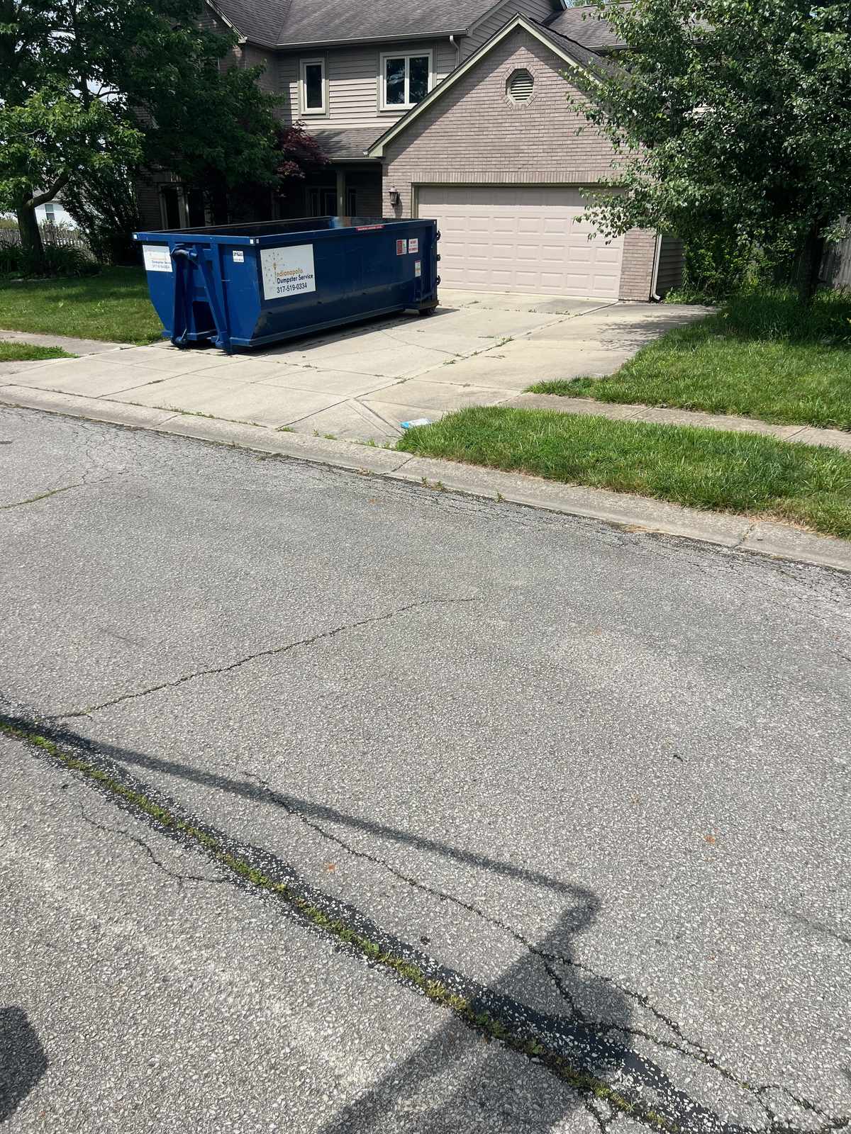 A navy Indianapolis Dumpster Service roll off container in Indianapolis. At the top of the driveway, seen from the street.
