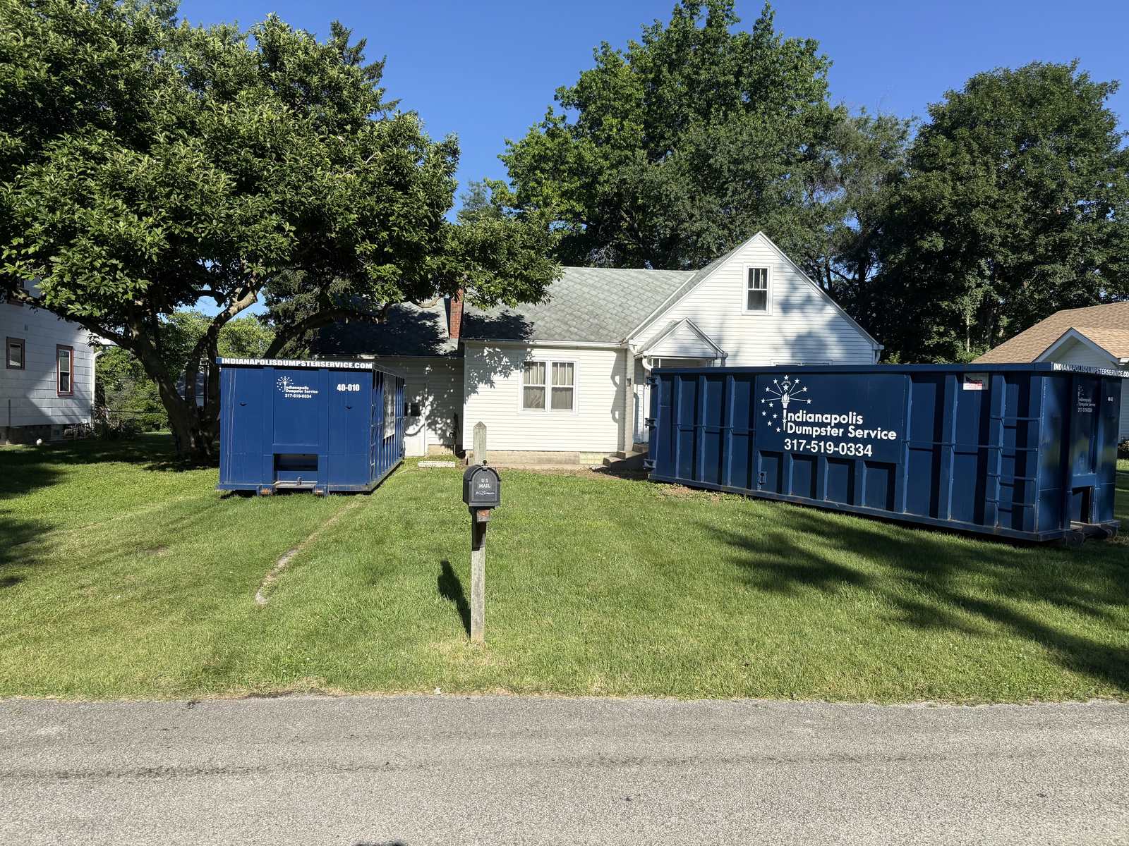 A navy Indianapolis Dumpster Service roll off container in Indianapolis. Two dumpsters on one property for a whole-house cleanout.