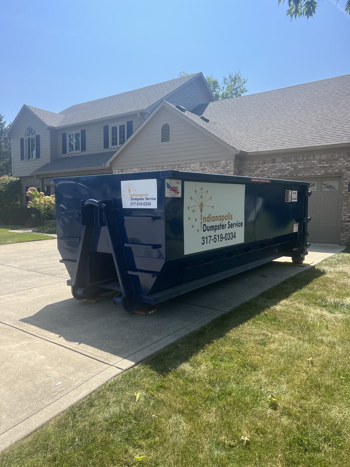 A navy Indianapolis Dumpster Service roll off container. A new build with the dumpster on the new driveway.