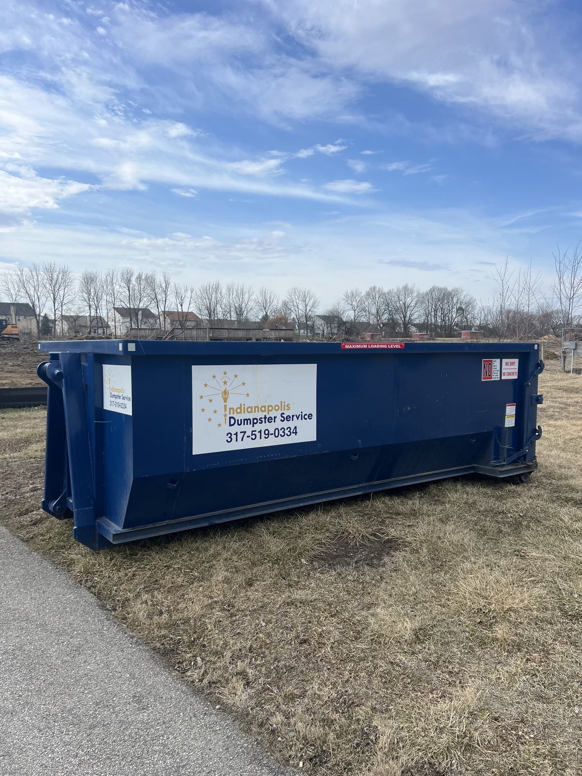 A navy Indianapolis Dumpster Service roll off container in Whitestown. On open ground in Whitestown.