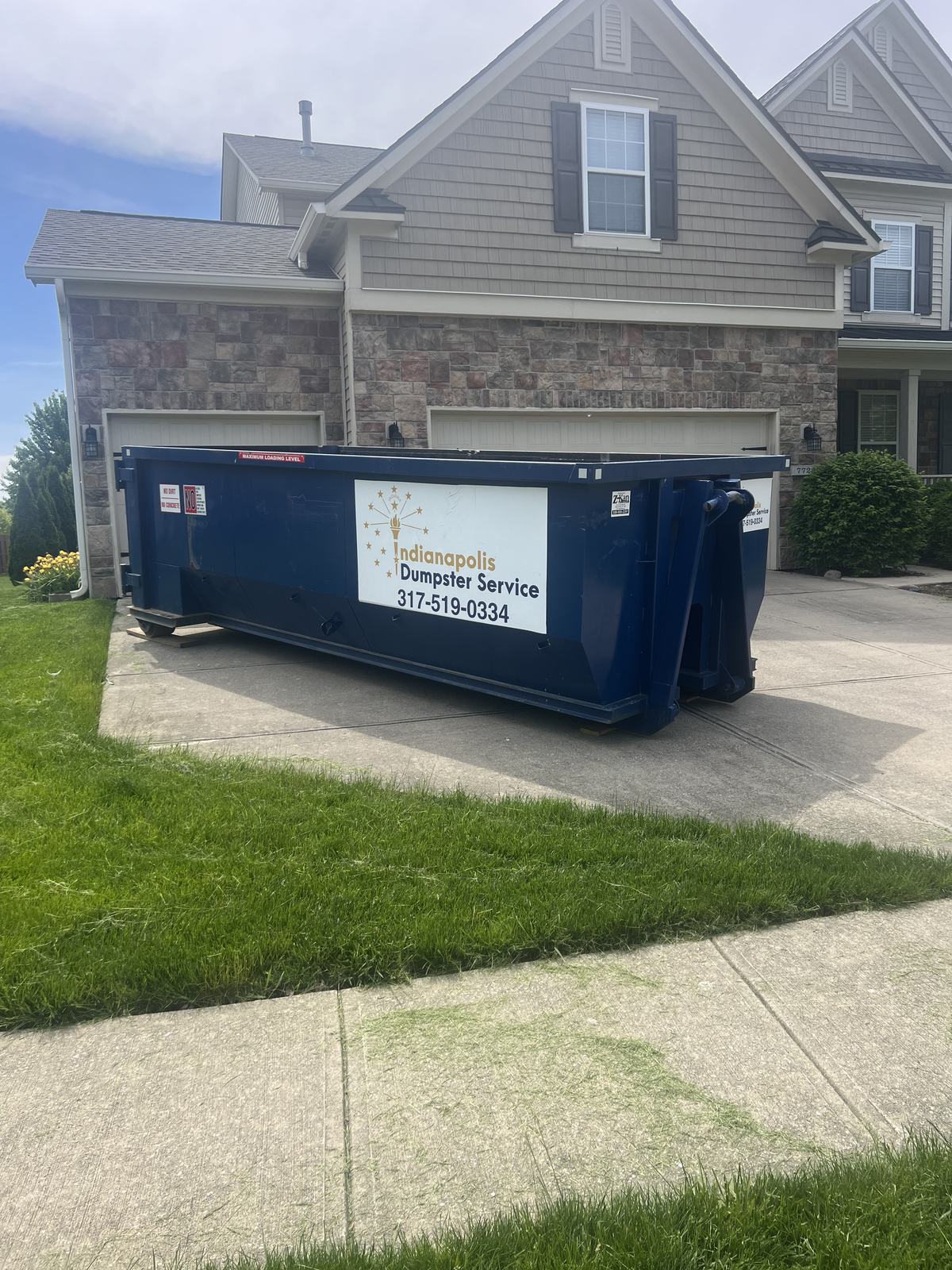A navy Indianapolis Dumpster Service roll off container in Zionsville. On a new concrete driveway.
